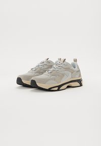 Beżowe i szare sneakersy z połączeniem siateczki i zamszu, sznurowany design, gumowe podeszwy oraz czarny akcent na zewnętrznej krawędzi.