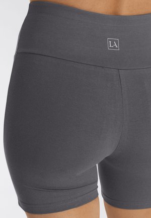 Graue Sportshorts mit hohem Bund, glatter Textur und minimalen Nähten, mit einem Logo am Bund.