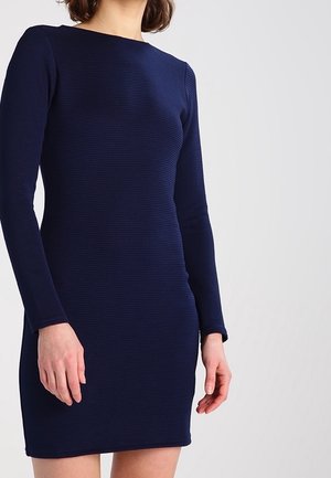 Abito lungo a maniche lunghe in maglia blu navy con silhouette aderente. Presenta un collo rotondo e una texture liscia. Termina sopra il ginocchio.