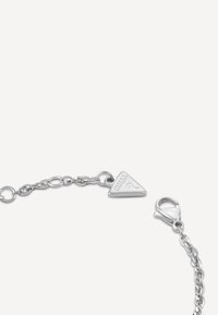 Bracciale in metallo argento con un ciondolo a forma di triangolo con la scritta "GUESS" incisa, design a catena collegata e chiusura a moschettone.
