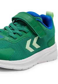 Zielone siatkowe buty sportowe z rzepem, kontrastującymi niebieskimi akcentami oraz białą gumową podeszwą z dekoracyjnymi szarymi wzorami.