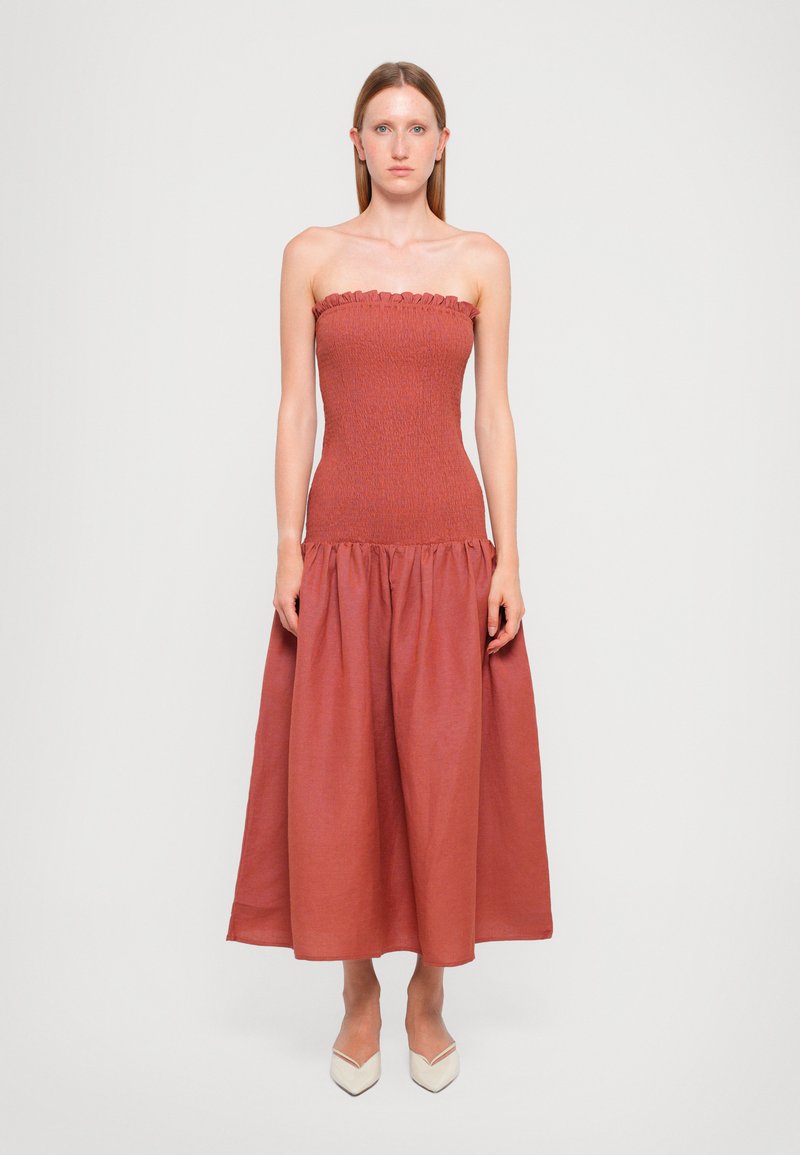 Strapless, rust-colored dress with a smocked bodice, flared bottom, and ruffled neckline detail. Smooth texture, knee-length hem.