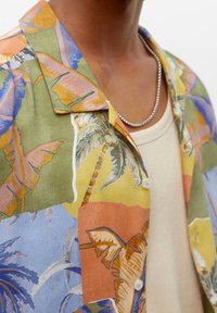 Chemise à manches courtes en tissu léger avec un imprimé tropical multicolore présentant des feuilles de palmier, des boutons et un col classique.