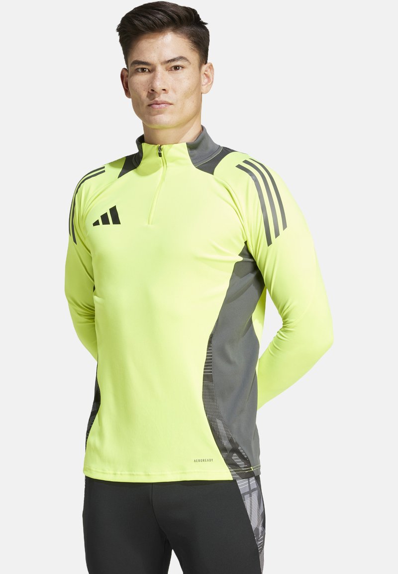 Maglietta atletica a maniche lunghe di colore giallo neon con dettagli grigi, zip a quarto e pannelli laterali testurizzati; presenta il logo Adidas sul petto e sulla spalla.