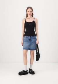 Black fitted tank top, denim skirt, chunky black platform clogs, white socks, and a small black bag, standing against a white background.