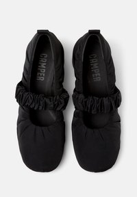 Ballerine in tessuto nero con rifiniture arricciate attorno all'apertura, tomaia imbottita e punta arrotondata e liscia. La soletta interna presenta il marchio "CAMPER".