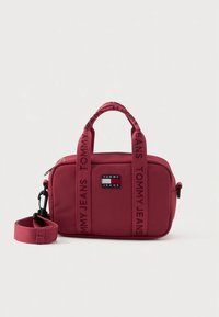 Borsa rossa in nylon con doppio manico e tracolla removibile, presenta il logo "TOMMY JEANS" nero sulla parte anteriore e dettagli in nastro coordinato.