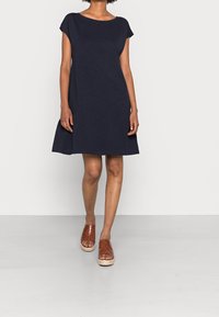 Sinih el dress lyhyillä hihoilla, rento malli ja levenevä helma. Kevyestä kankaasta valmistettu, yhdistetty ruskeisiin kudottuihin liukuvaatteisiin.