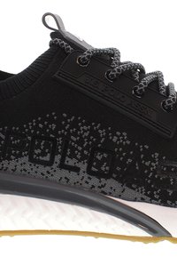 Mustat urheilukengät, joissa on teksturoitu neulepinta, harmaat nauhat ja kumipohja, valkoinen välikerros sekä kohokuvioitu brändäys.