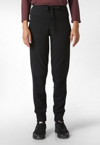 Zwarte joggingsbroek van zacht materiaal, voorzien van een trekkoord in de taille, taps toelopende pijpen en ribgebreide manchetten. Subtiele logodetail aan de zijkant.