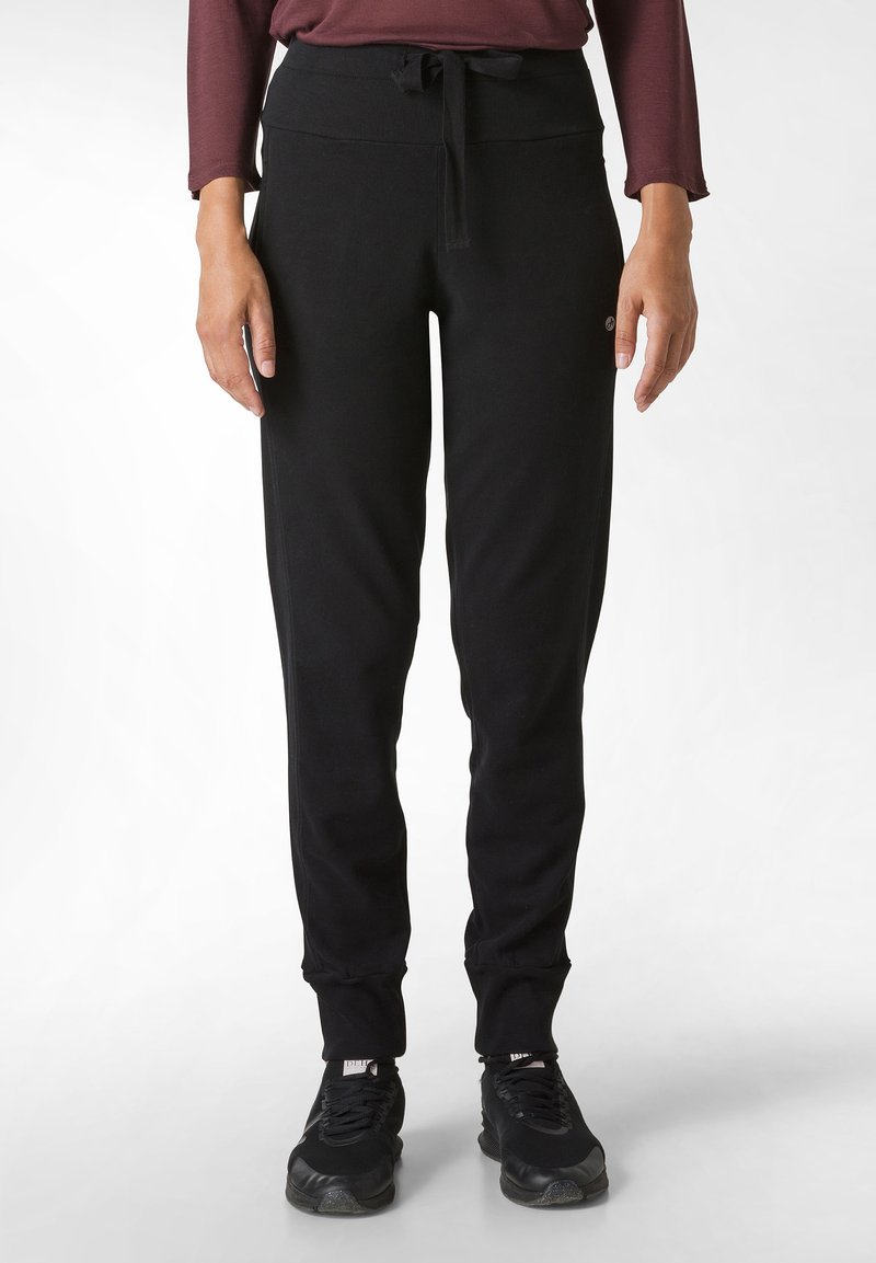 Zwarte joggingsbroek van zacht materiaal, voorzien van een trekkoord in de taille, taps toelopende pijpen en ribgebreide manchetten. Subtiele logodetail aan de zijkant.