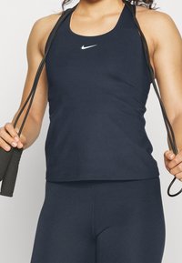 Canottiera sportiva blu navy realizzata in tessuto morbido, con design a schiena scoperta e un piccolo logo Nike bianco sul petto.