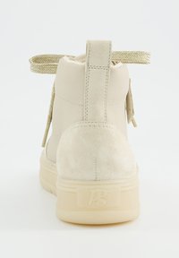 Beige High-Top-Sneaker mit texturiertem Stoff-Fersenbereich, dicker Sohle, hinterem Zuglasche und geflochtenem Fersenloop, von hinten auf einem weißen Hintergrund gezeigt.