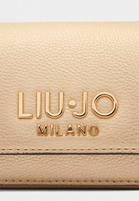 Portefeuille en cuir beige avec un logo « LIU.JO MILANO » en relief doré, texture lisse avec des détails fins et un design épuré et minimaliste.