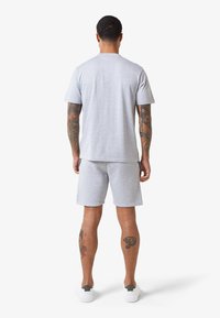 Conjunto de camiseta de algodón gris y pantalones cortos, con mangas cortas, un diseño sencillo y un corte relajado, combinado con zapatillas blancas.