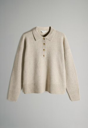 Bež kudumiga sviiter, millel on kraed, viis kuldset nööpi, soonikkoes varrukad ja ääred. Pehme tekstuur ja mugav lõige.