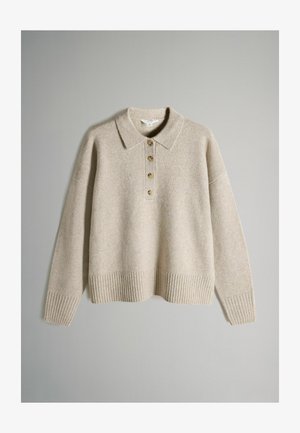 Bež kudumiga sviiter, millel on kraed, viis kuldset nööpi, soonikkoes varrukad ja ääred. Pehme tekstuur ja mugav lõige.