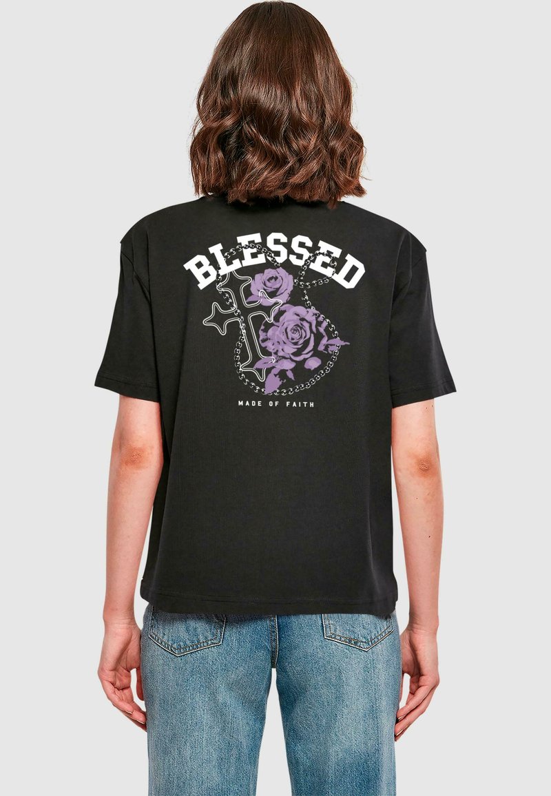 Svart t-skjorte med hvit tekst "BLESSED" og lilla roser med korsdesign. Korte ermer, standard passform, i bomullsmateriale.