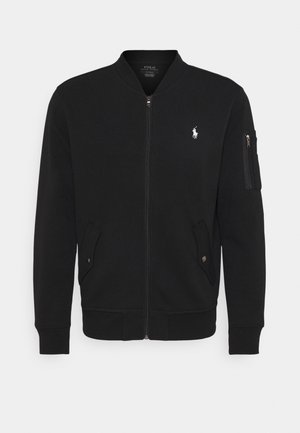 Sort bomberjakke med lynlås, ribstrikkede manchetter og kant, forlommer med trykknapklapper, lynlåslomme på ærmet og lille hvid Polo Ralph Lauren-logo på brystet.