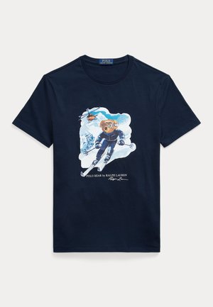Navy cotton t-shirt featuring a graphic of a bear skiing, wearing goggles, with a helicopter above and snowy mountains in the background.
