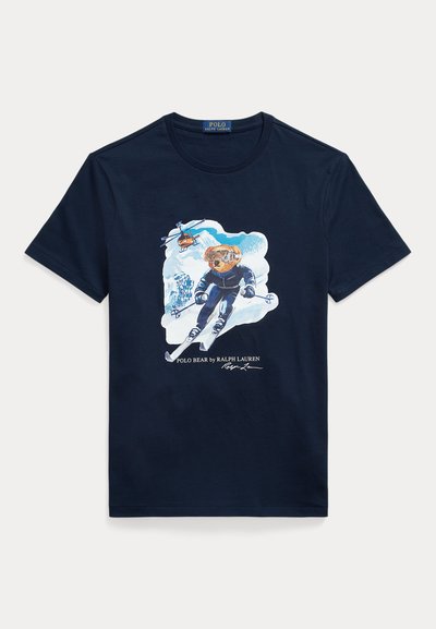 Navy cotton t-shirt featuring a graphic of a bear skiing, wearing goggles, with a helicopter above and snowy mountains in the background.