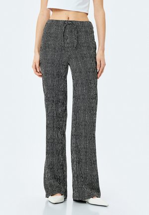 Zwart-wit gestreepte wijde broek met een drawstring taille, gemaakt van een zachte stof met een gestructureerde afwerking.