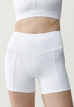 Witte, nauwsluitende atletische short met hoge taille op een persoon, met nadruk op de soepele naden en rekbare, ondersteunende stof.