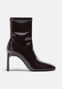 Stivaletto alla caviglia in pelle verniciata nera con tacco, punta affilata e silhouette elegante e aderente. Presenta un alto tacco a spillo e un design senza cuciture.