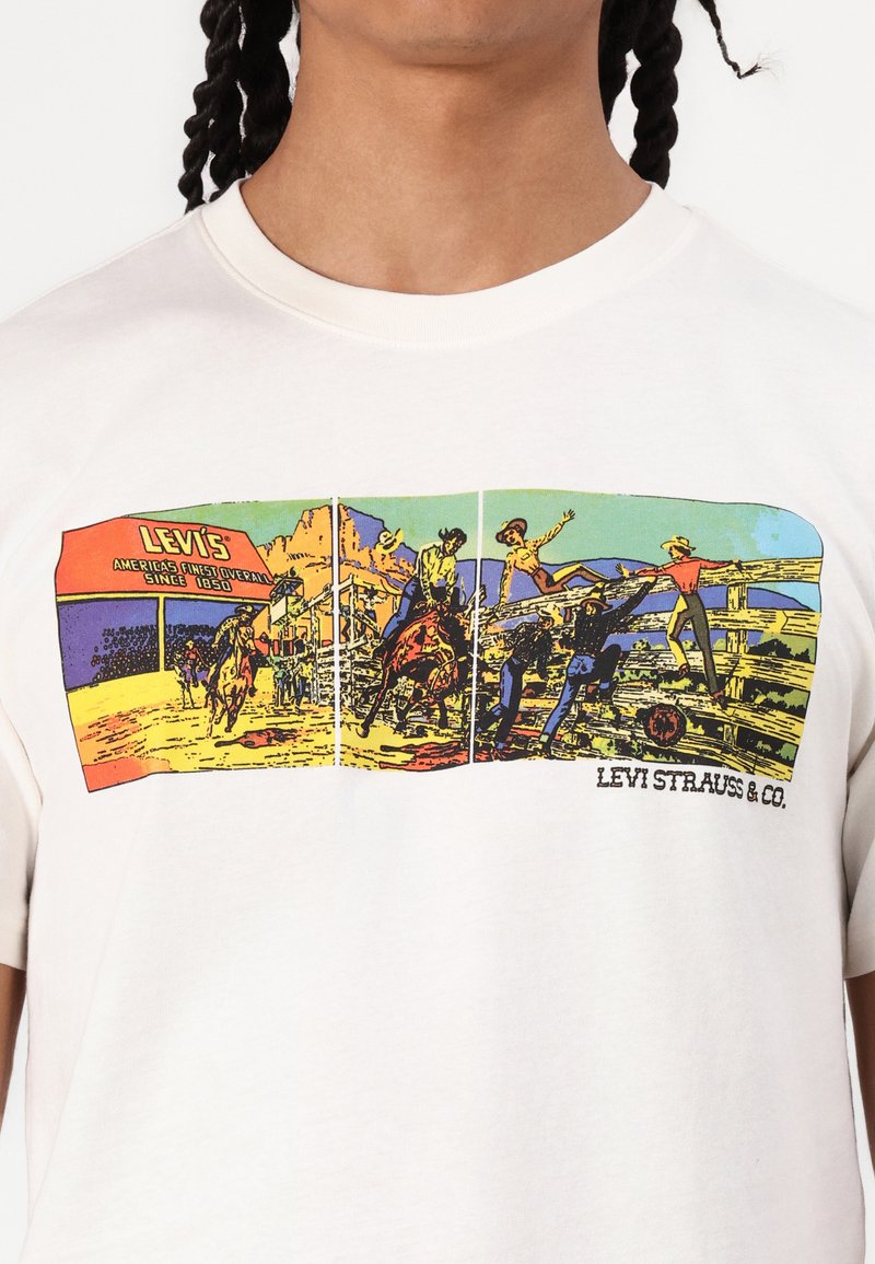 Weißes Baumwoll-T-Shirt mit einem bunten Grafikdruck, der Cowboys und Ranch-Szenen darstellt. Der Schriftzug "LEVI'S" erscheint über dem Design.