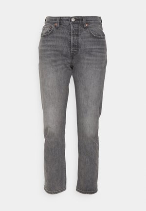 Jeans noirs en denim, avec une coupe droite, cinq poches et une fermeture standard à boutons et à glissière. Un léger délavage est visible.