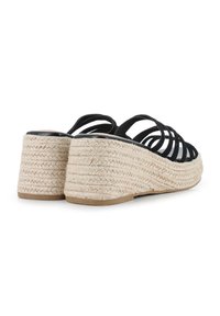 Sandalias de cuña negras con tiras y plataforma de yute trenzado. El tacón presenta un acabado texturizado en beige y una suela negra lisa.