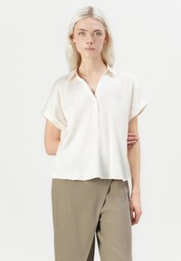 Kurzärmlige, cremefarbene Bluse aus leichter, glatter Stoffqualität. Mit Kragen, Knopf-Front und einem lässigen Schnitt mit geradem Saum.