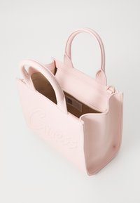 Sac à main synthétique rose avec le logo "Guess" en relief, poignées courtes, ouverture sur le dessus et poche intérieure zippée. Texture lisse, forme structurée.