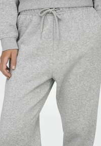 Grijze fleece joggers met een elastische tailleband, een trekkoord en zijzakken. Zachte textuur, relaxte pasvorm en subtiel gemêleerd patroon.