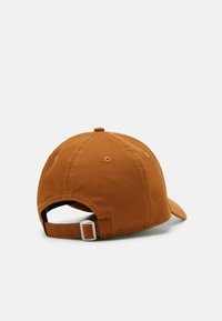 Gorra de béisbol de algodón marrón con visera curvada, correa trasera ajustable y ojales cosidos para ventilación, con un acabado texturizado.