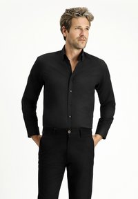 Zwarte langslavige overhemd met knopen en kraag, en bijpassende zwarte broek, met een gladde textuur en klassieke pasvorm.