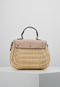 Tkana torebka z wikliny z gładką różową klapką na górze, złotymi elementami i usztywnionym kształtem. Posiada krótki uchwyt do noszenia.