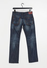 Denims i mörkblått med en urtvättad finish, med två bakfickor, kontrasterande sömmar och en brun läderetikett på midjan.