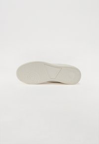 Fehér sneaker talp, textúrált gumival. Kör- és háromszögminták találhatók a külső talpon a jobb tapadás érdekében. Simára polírozott felület.