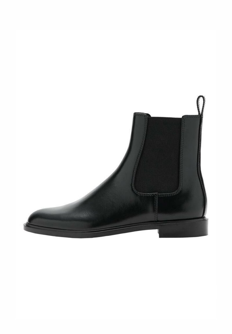 Botte Chelsea en cuir noir avec panneau latéral élastique, bout arrondi, talon bas et languette à l'arrière. Texture lisse et design minimaliste.