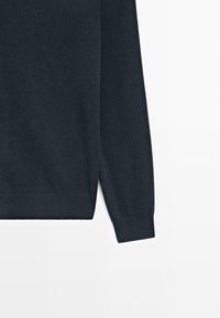 Ciemnoniebieski sweter z ribbowymi mankietami i dołem, wykonany z miękkiego, teksturowanego materiału dzianinowego. Prosty design bez wzorów i ozdób.