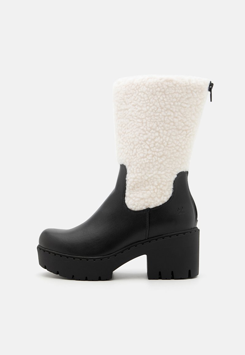 Črne usnjene gležnjarje z belim umetnim ovčjim krznom, masivnim črnim podplatom, ukrivljeno obliko in stransko zadrgo.