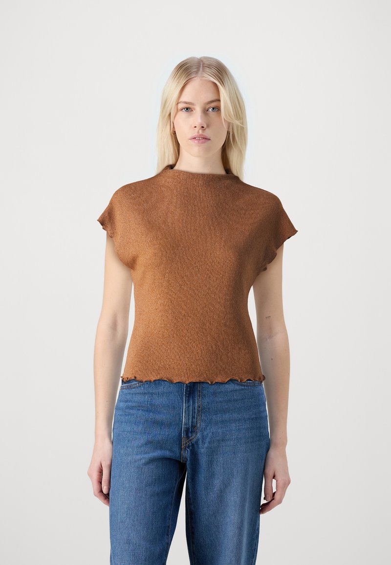 Bruine, geribbelde trui met een hoge halslijn en kapmouwen. Heeft een golvende zoom. Gecombineerd met een blauwe jeans.