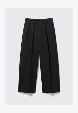 Pantalons larges noirs en tissu léger, avec une taille élastique et un cordon de serrage, sans poches visibles.