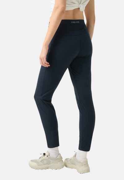 Námořnické modré, přiléhavé kalhoty vyrobené z elastického materiálu s kapsou na zip na zadní straně a kontrastním logem na pasu. Hladká textura, elegantní design.