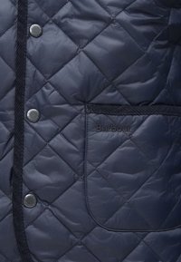 Τμήμα ναυτικού τζάκετ με κέντημα διαμαντιών, τσέπη με μαύρη επένδυση και μεταλλικά κουμπιά με ανάγλυφο το όνομα της μάρκας.