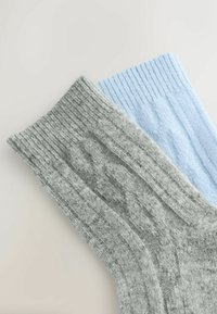 Pair of ribbed socks in light gray and soft blue. Features a textured design with cable knit accents and elasticized cuffs.