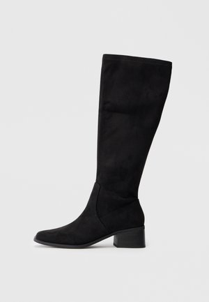 Mustad kummikud, mis ulatuvad põlveni, suede-sarnase materjaliga, terava varbaga ja plokkninaga. Küljel olev õmblusdetail rõhutab kuju.