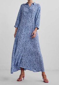 Blå blomstret midi skjortekjole med lange ærmer, knaplukning foran og svævende silhuet. Har et let stof og en uregelmæssig kant.