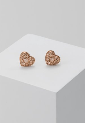 Boucles d'oreilles clous en forme de cœur en or rose, ornées de multiples petits cristaux scintillants, présentées sur un piédestal géométrique blanc.